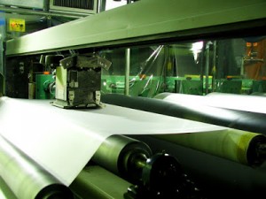 After the sheet is calendered, it is passed through a series of rollers, which impart a surface finish.  In this manufacturing stage, the thickness of the sheet is measured continually across the web to ensure product consistency. Photo courtesy of Achilles USA, Inc.